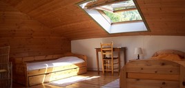  Gite isère Au Vieux Four à Pain La grande chambre Belledonne. Un lit double, trois lits simples dont un lit gigogne. Il y a des stores d'occultation aux fenêtres de toit.